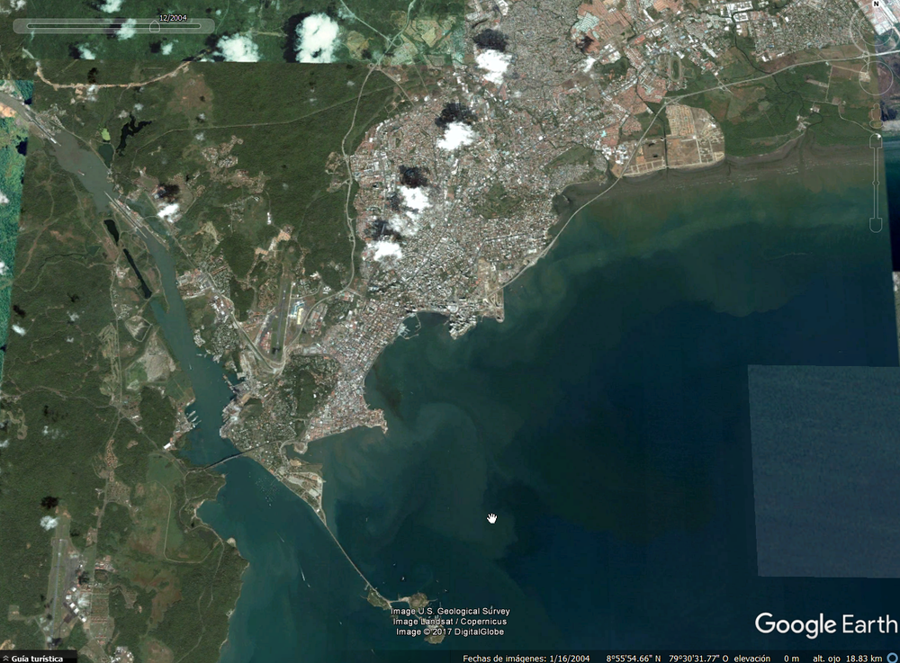 Imagen satelital de una ciudad costera con áreas urbanas adyacentes a una gran bahía, con aguas cristalinas y diversos patrones de uso del suelo.