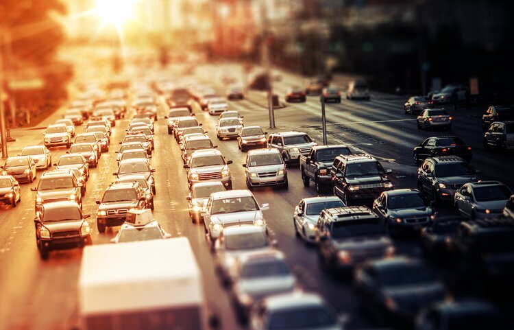 Tráfico intenso en una carretera de la ciudad durante la puesta de sol, centrándose en los bulliciosos carriles de automóviles iluminados por el cálido resplandor de la luz del sol.