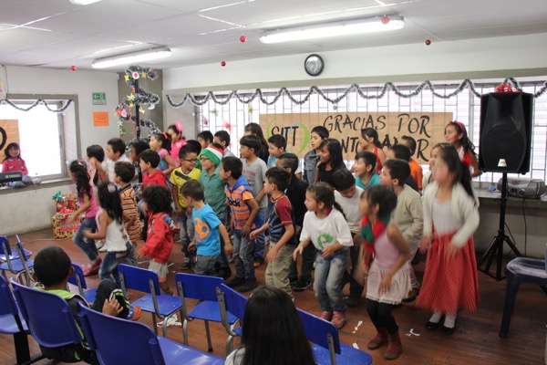 Los niños participan en una actividad en el aula con un cartel que dice "gracias por este año" de fondo.