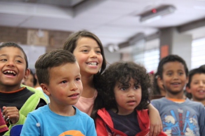 Un grupo de niños diversos sonriendo y riendo en un salón de clases.