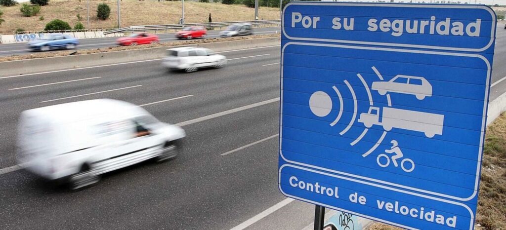 Señal de control de velocidad del tráfico en una carretera con vehículos en movimiento, que indica el uso del radar para controlar la velocidad.